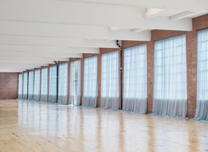 Hallway of large windows with blue translucent curtains