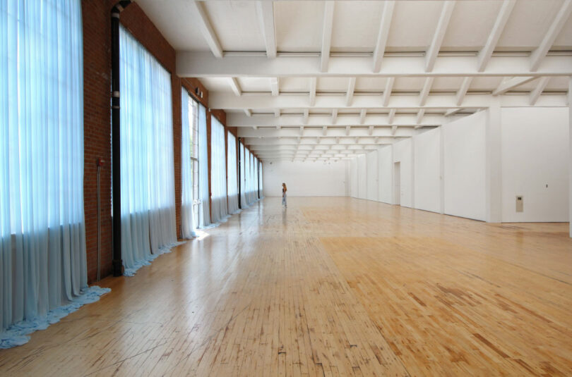 Woman admiring Gonzalez-Torres' blue curtains in empty room