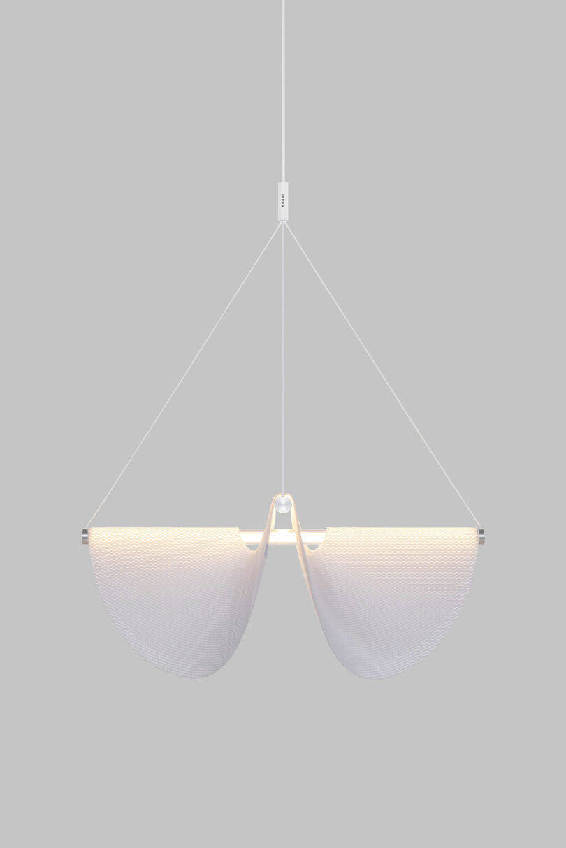 The Drape Light by Jamie Wolfond, featuring two curved panels suspended by thin cables against a gray background.