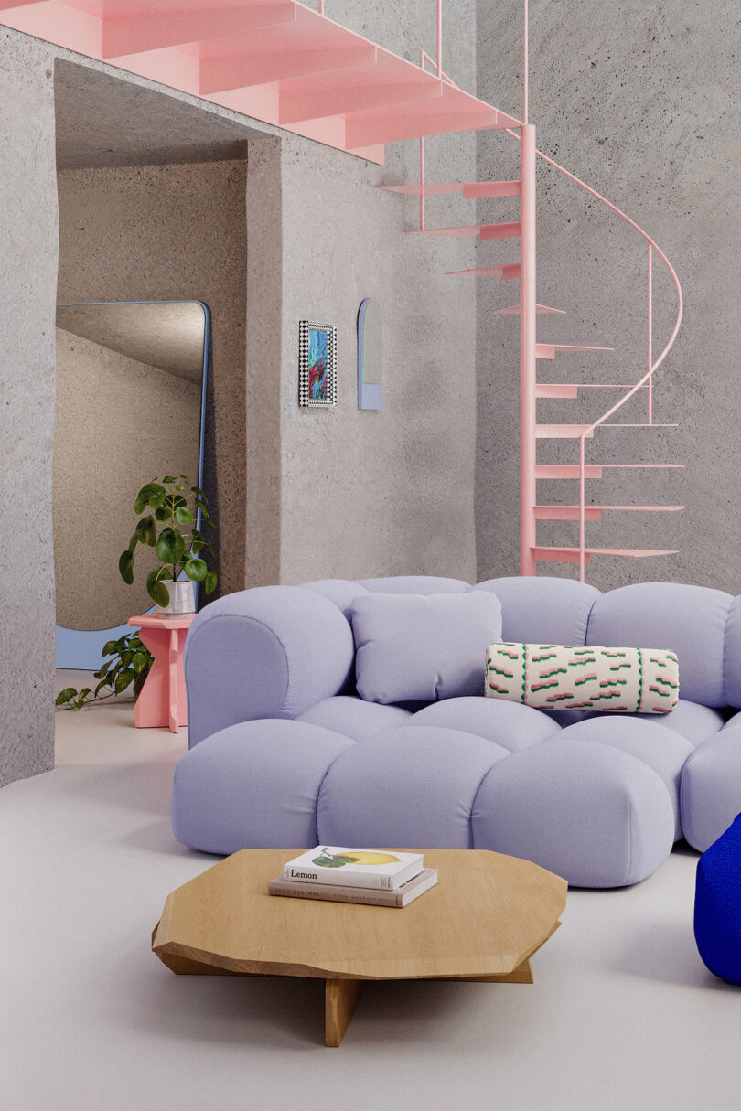 A modern living room features a pastel blue sofa, a wooden coffee table with books, a plant on a pink stand, and a pink spiral staircase against a textured gray wall