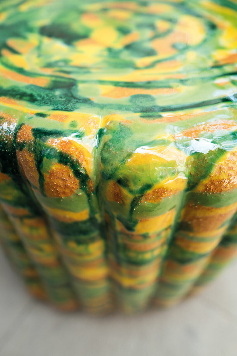 Close-up of Anemone by Nicolò Morales for Paola Lenti, a cylindrically shaped object with a glossy, swirled green and yellow pattern on its surface.