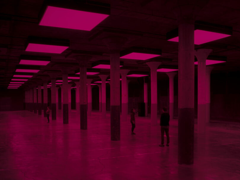 Visitors standing in columned room under red light