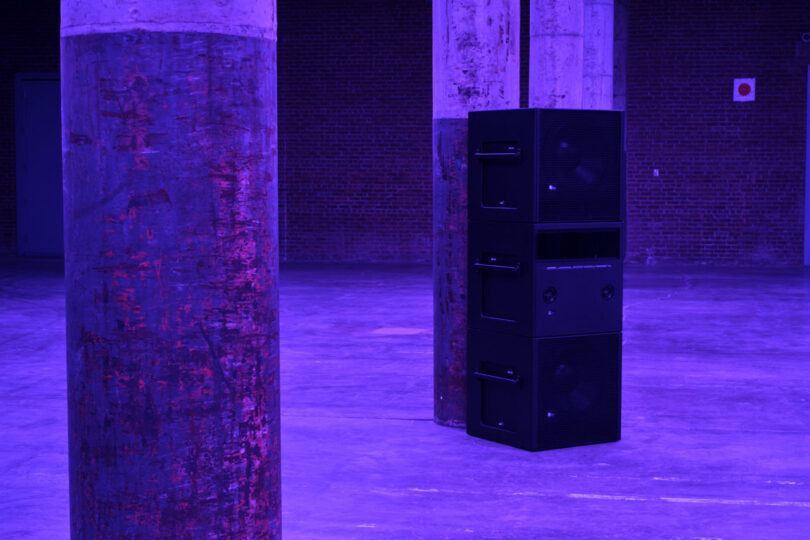 Stack of speakers next to pillar in purple light